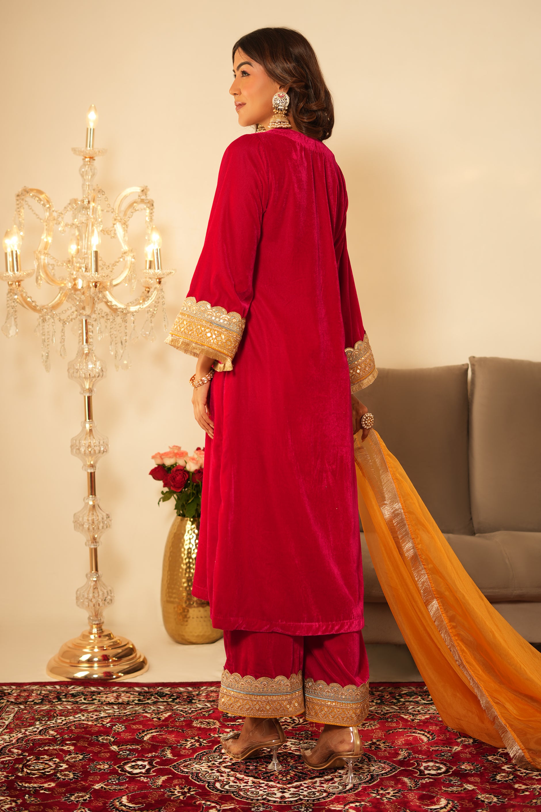 Woman wearing Pink Velvet Kurta with Pants Set of 2 featuring intricate contrast lace detailing on neckline, sleeves and pant hem, V neckline, full sleeves, and matching pink velvet pants