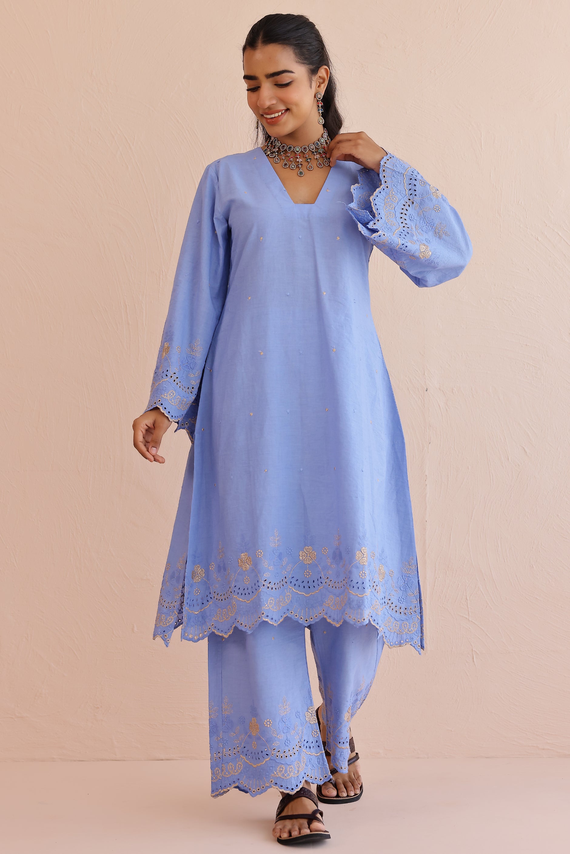 Woman wearing blue embroidered cotton A-line kurta with full sleeves and matching embroidered pants.