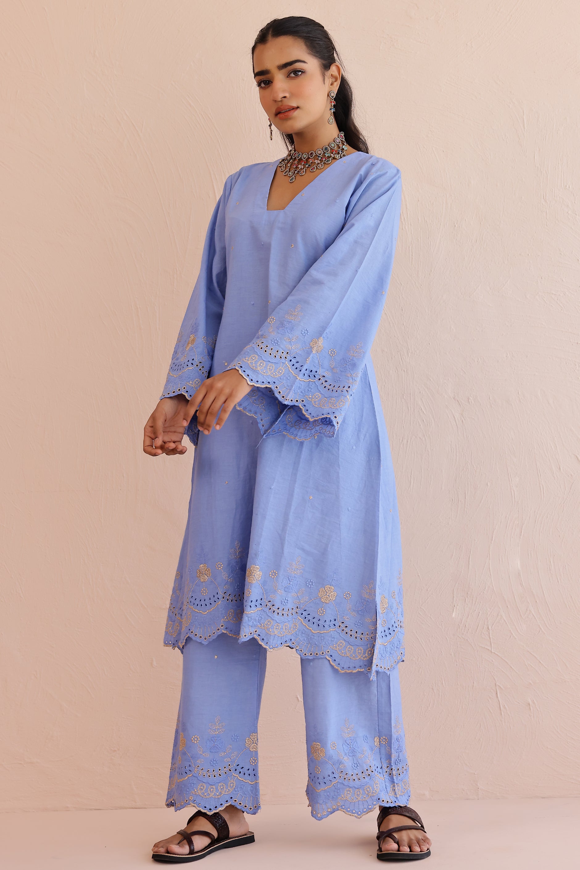 Woman wearing blue embroidered cotton A-line kurta with full sleeves and matching embroidered pants.