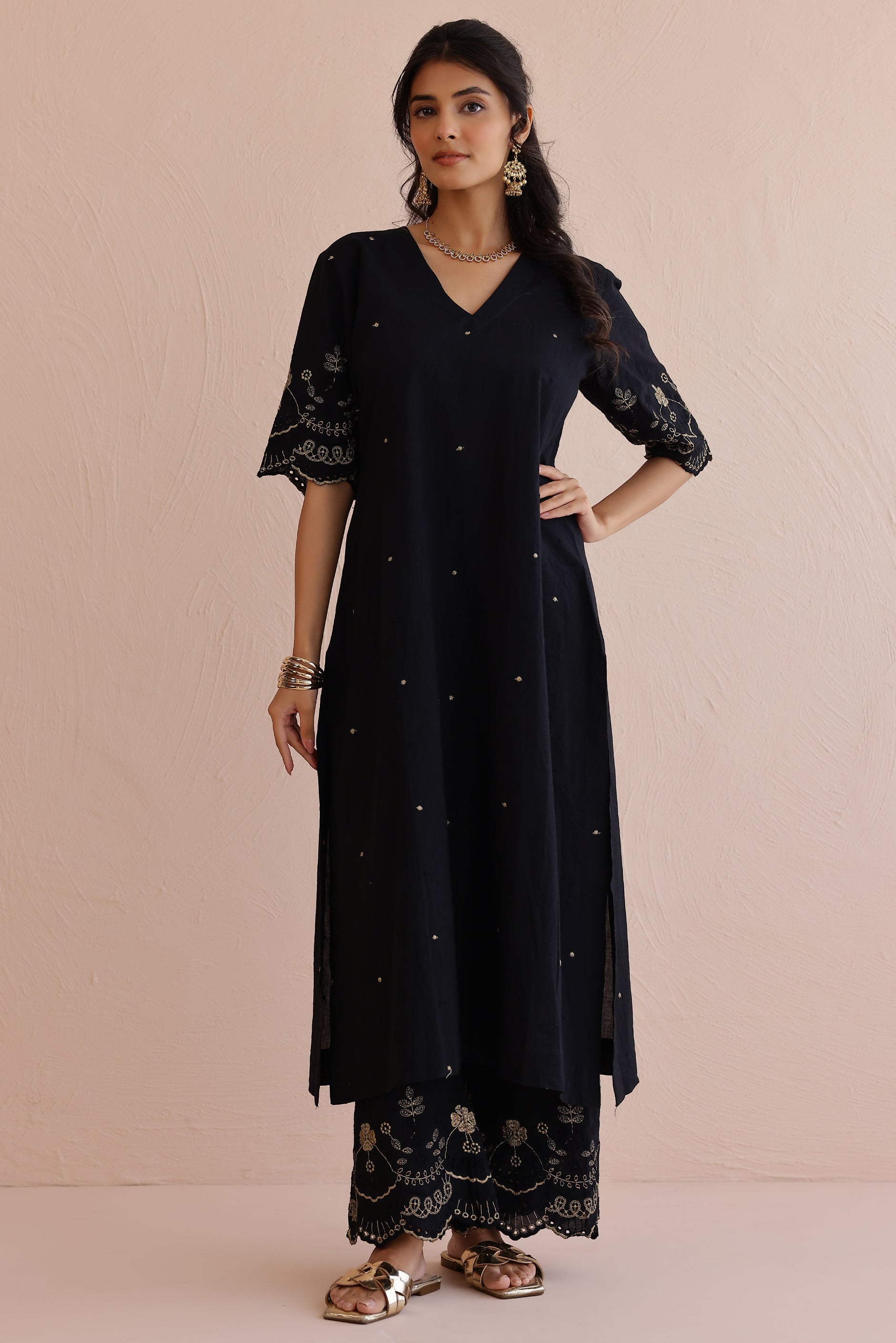 Woman wearing black embroidered cotton kurta with V-neckline, half sleeves, and matching embroidered pants.
