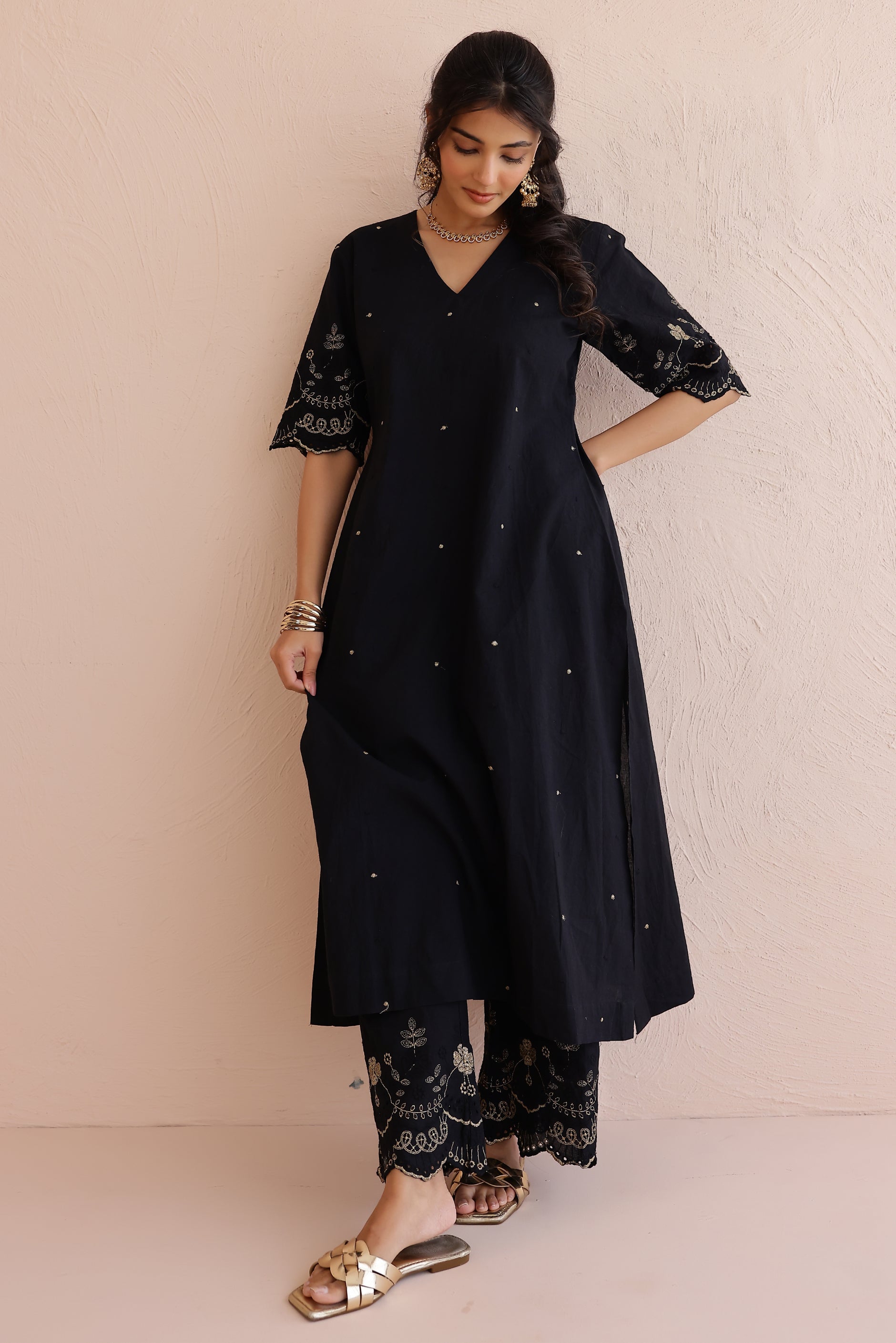 Woman wearing black embroidered cotton kurta with V-neckline, half sleeves, and matching embroidered pants.