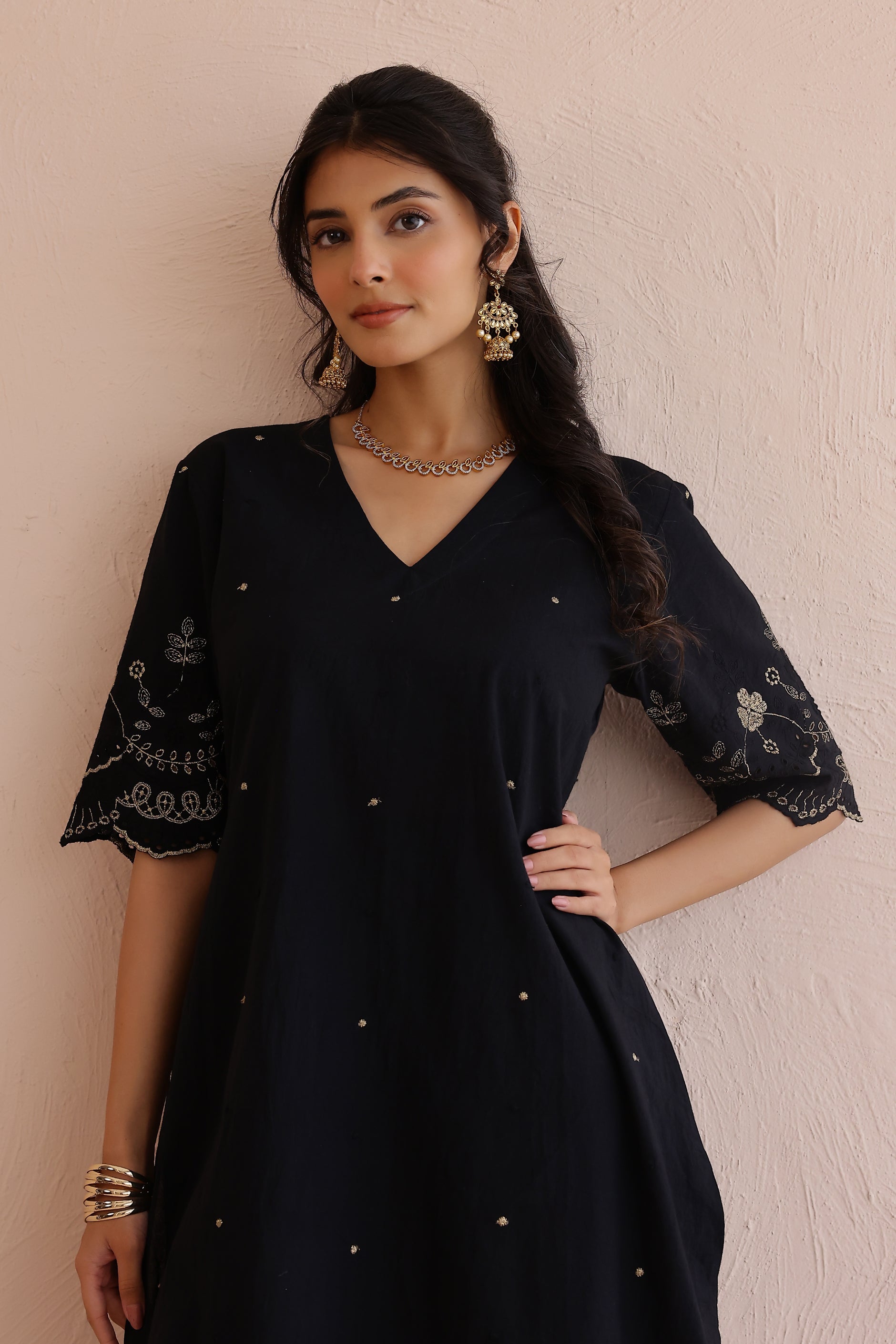 Woman wearing black embroidered cotton kurta with V-neckline, half sleeves, and matching embroidered pants.