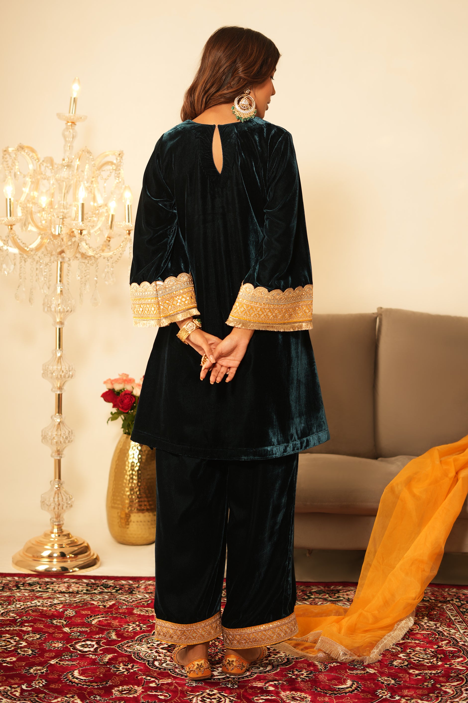 Woman wearing Blue Velvet Co-Ord Set featuring gota lace detailing on sleeves and hem, boat neckline, full sleeves, and matching green velvet pants with elastic waist and lace hem detailing