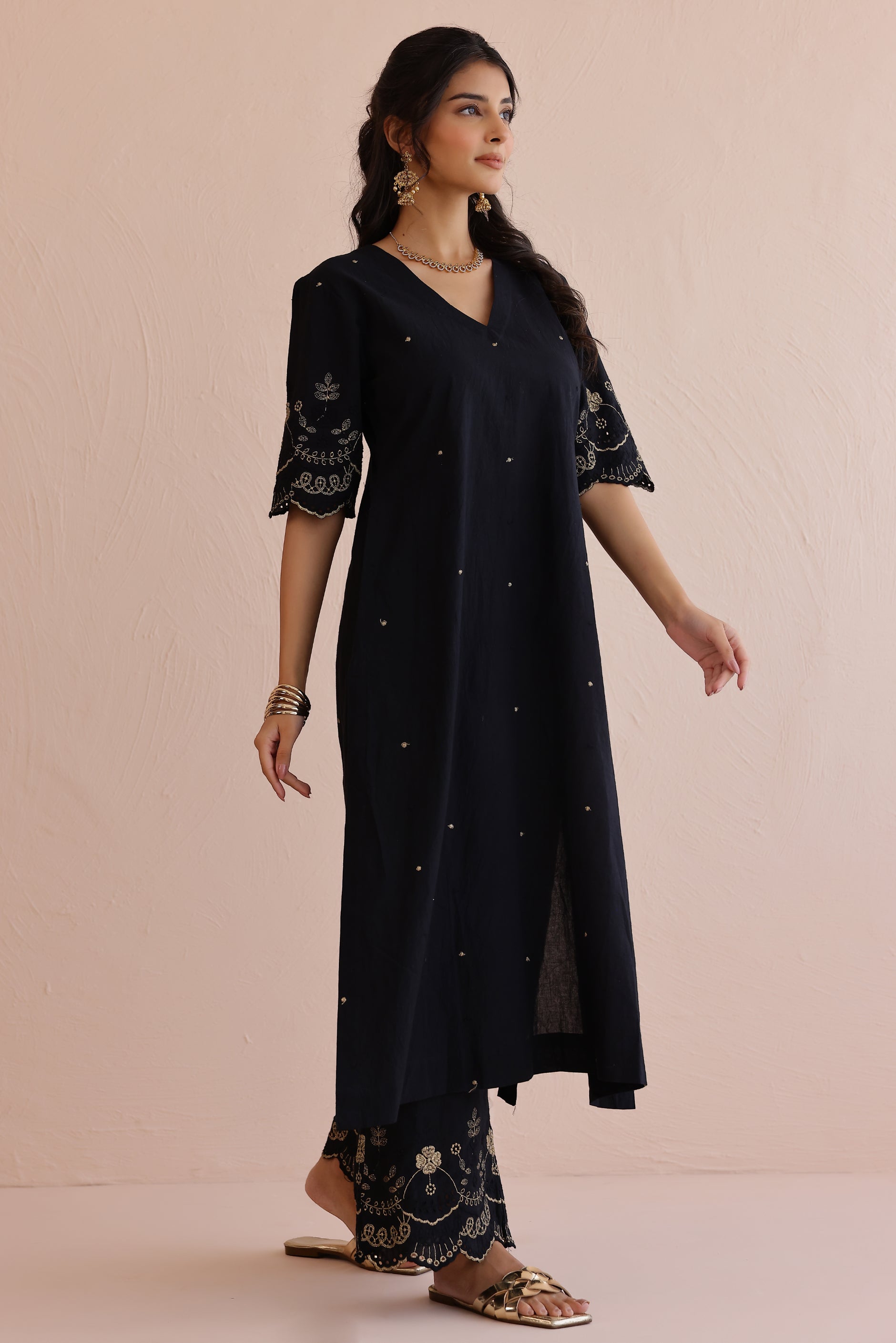 Woman wearing black embroidered cotton kurta with V-neckline, half sleeves, and matching embroidered pants.