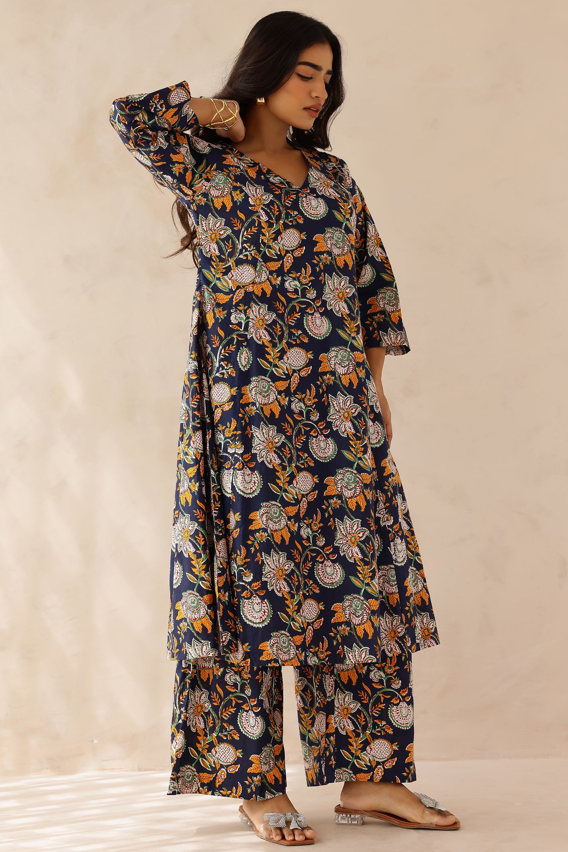 Woman wearing Blue Printed Cotton Kurta with Palazzo Set of 2 featuring blue and orange all over prints, V neckline, 3/4th sleeves, and matching printed palazzo with elastic waist