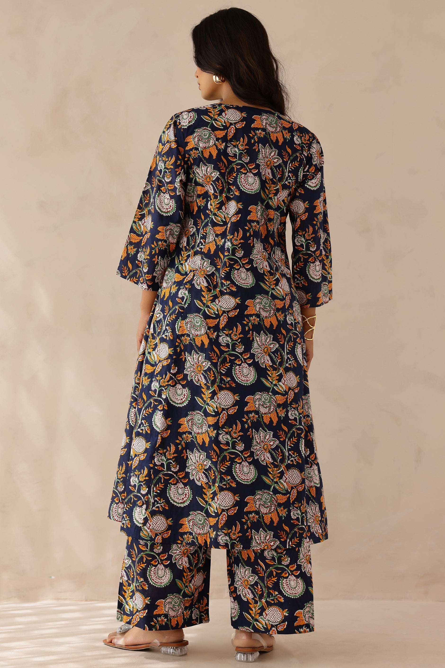 Woman wearing Blue Printed Cotton Kurta with Palazzo Set of 2 featuring blue and orange all over prints, V neckline, 3/4th sleeves, and matching printed palazzo with elastic waist
