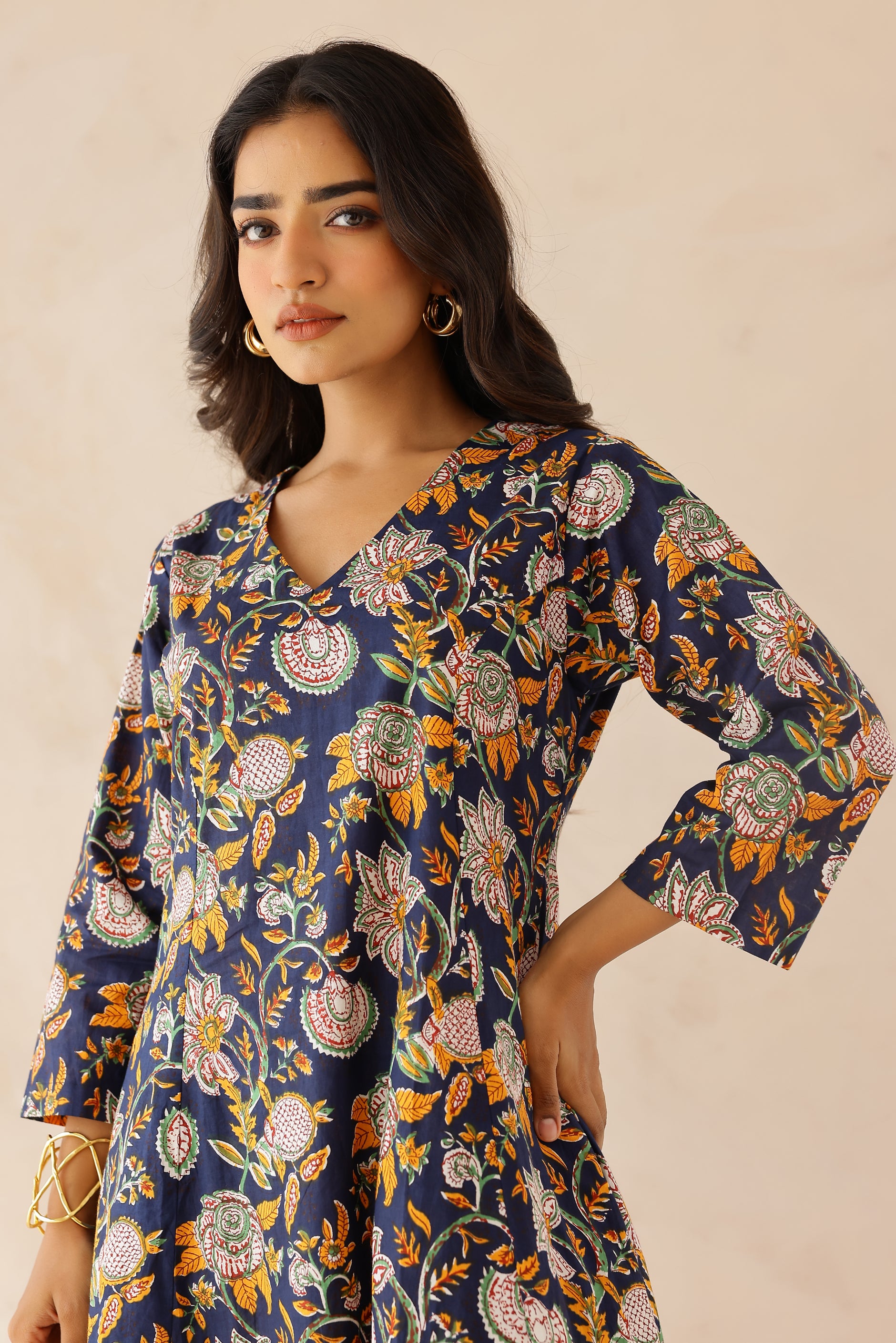 Woman wearing Blue Printed Cotton Kurta with Palazzo Set of 2 featuring blue and orange all over prints, V neckline, 3/4th sleeves, and matching printed palazzo with elastic waist