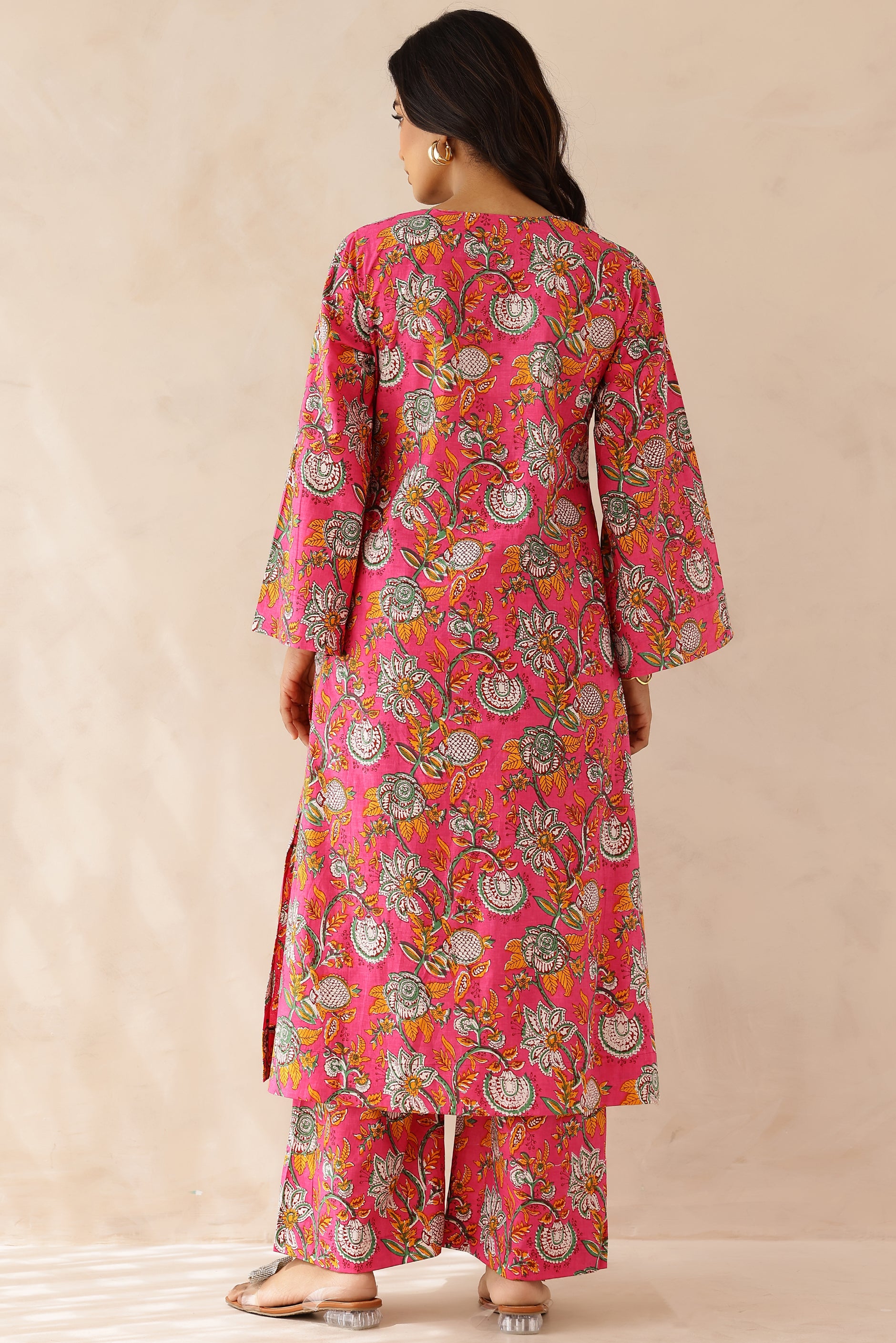 Woman wearing Pink Printed Cotton Kurta with Palazzo Set of 2 in light pink featuring all over prints, round to V neckline, full sleeves, and matching printed palazzo with elastic waist