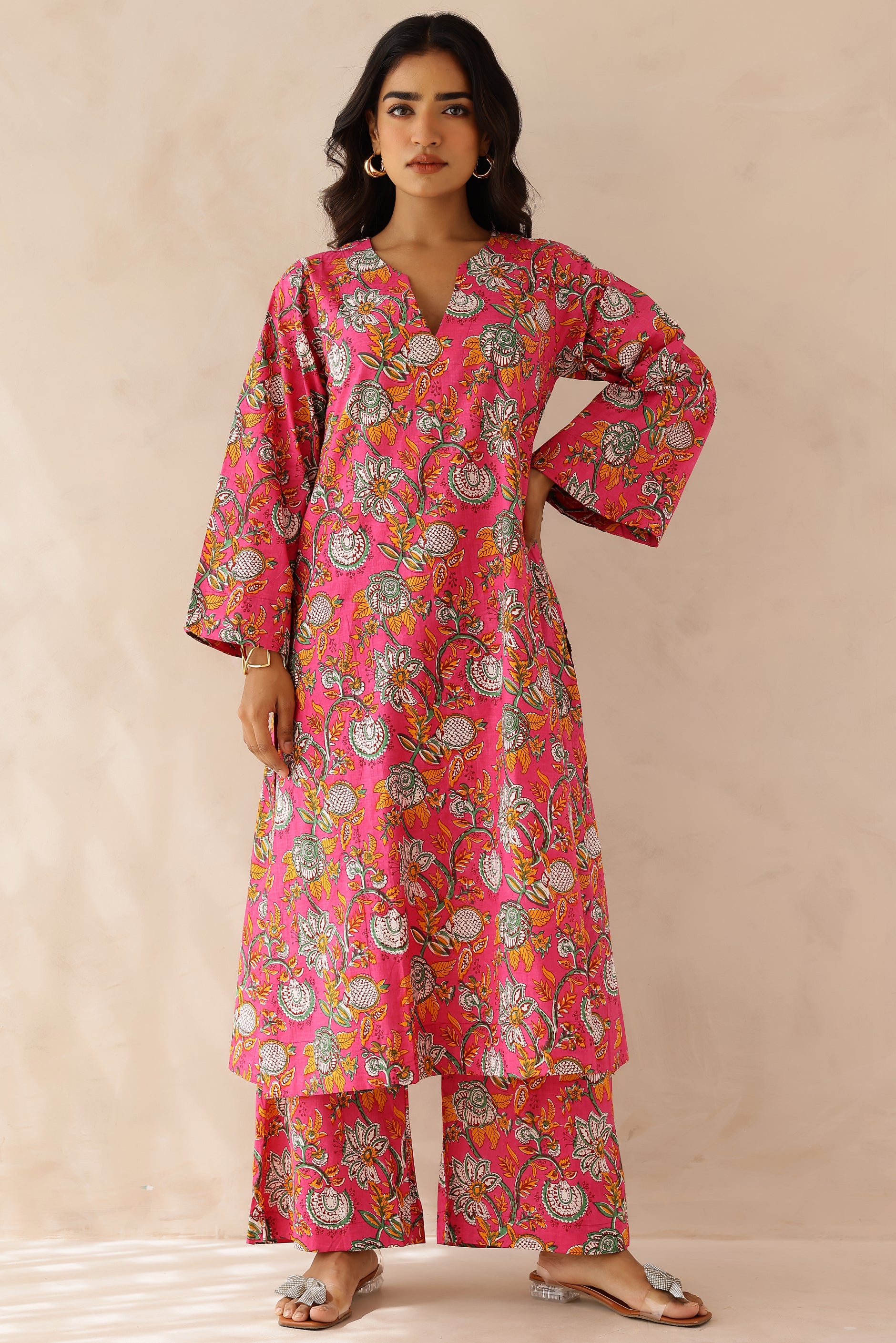 Woman wearing Pink Printed Cotton Kurta with Palazzo Set of 2 in light pink featuring all over prints, round to V neckline, full sleeves, and matching printed palazzo with elastic waist