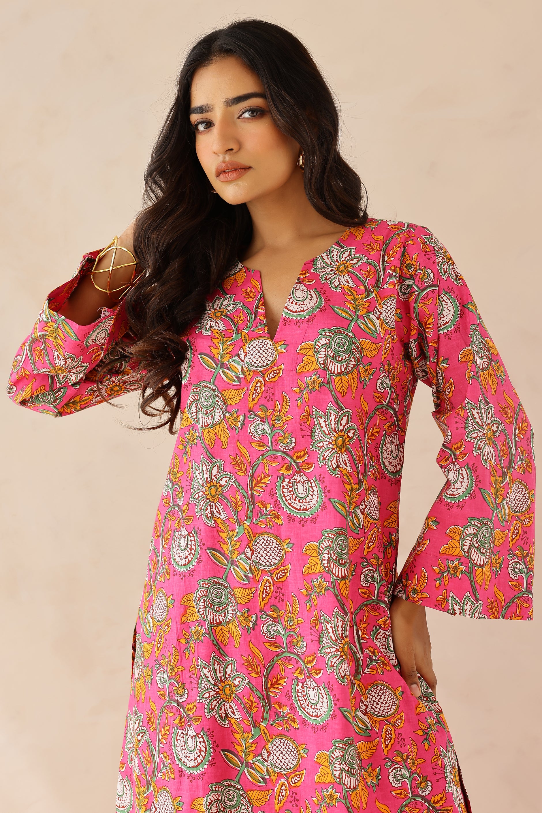 Woman wearing Pink Printed Cotton Kurta with Palazzo Set of 2 in light pink featuring all over prints, round to V neckline, full sleeves, and matching printed palazzo with elastic waist