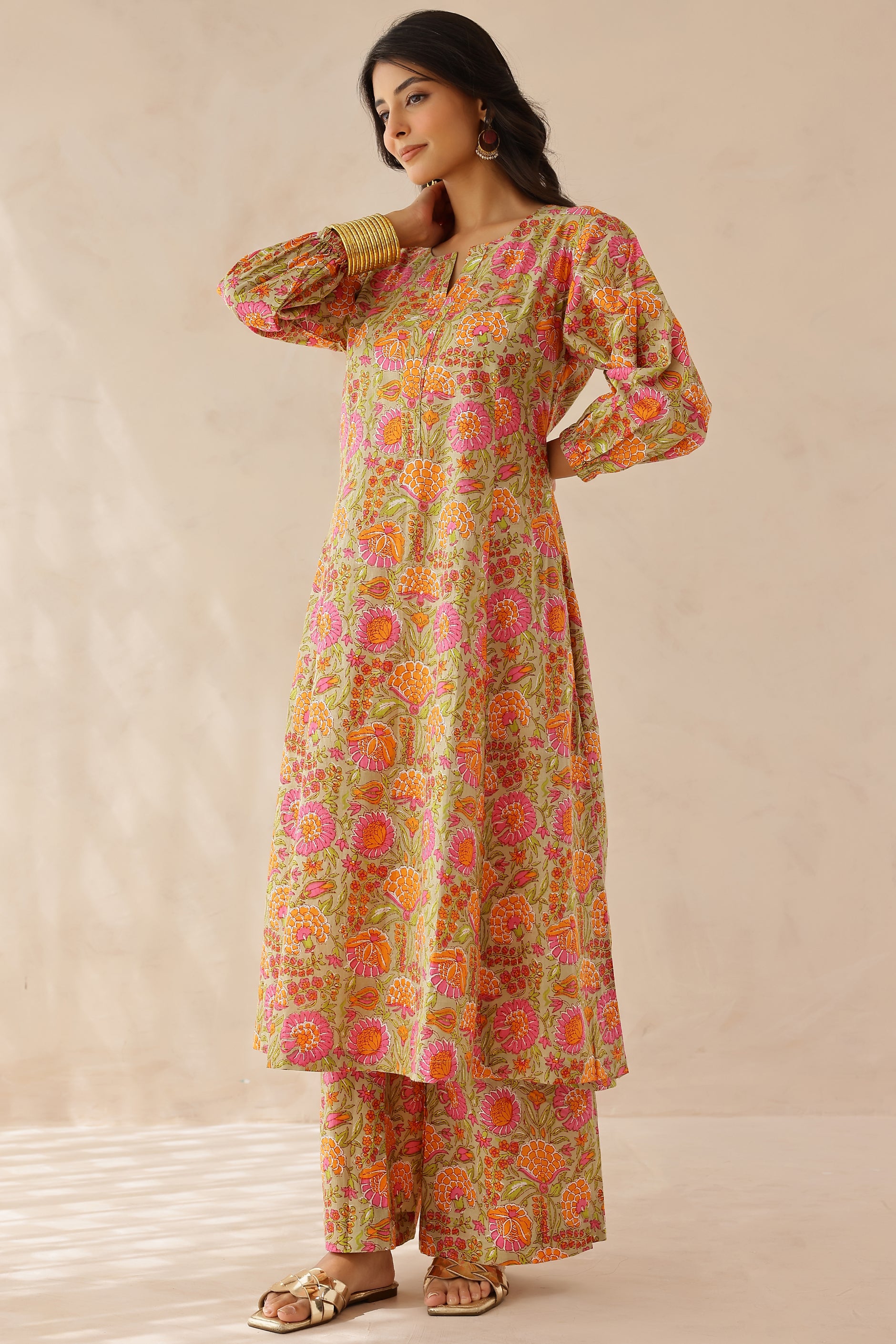 Woman wearing orange and pink printed cotton kurta with round V-cut neckline, 3/4 sleeves, and matching printed palazzo.