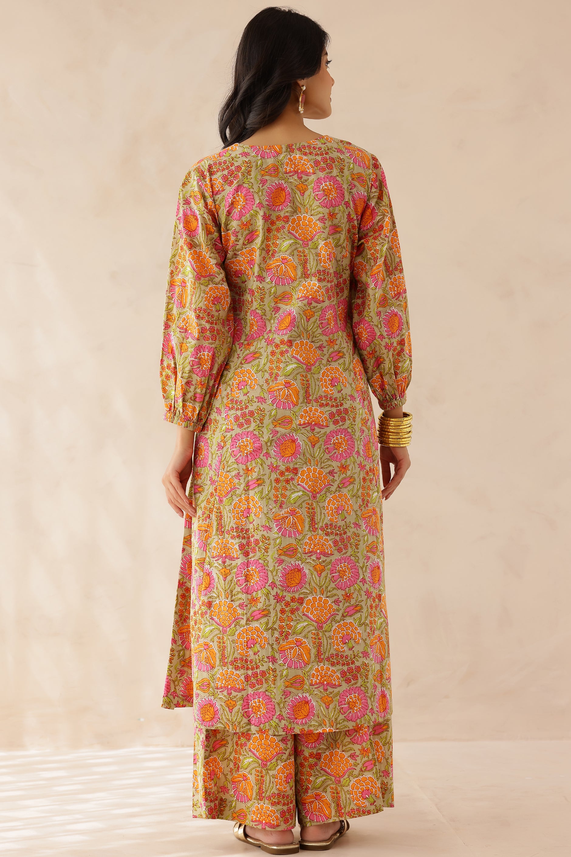 Woman wearing orange and pink printed cotton kurta with round V-cut neckline, 3/4 sleeves, and matching printed palazzo.