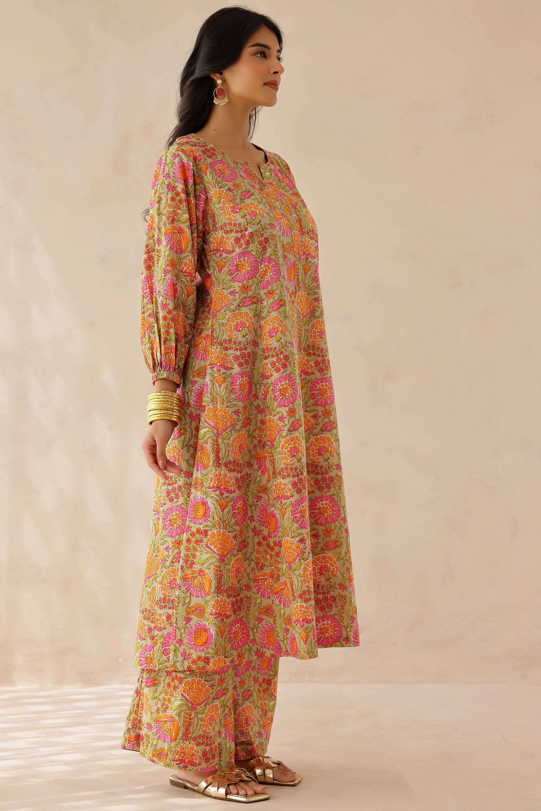 Woman wearing orange and pink printed cotton kurta with round V-cut neckline, 3/4 sleeves, and matching printed palazzo.