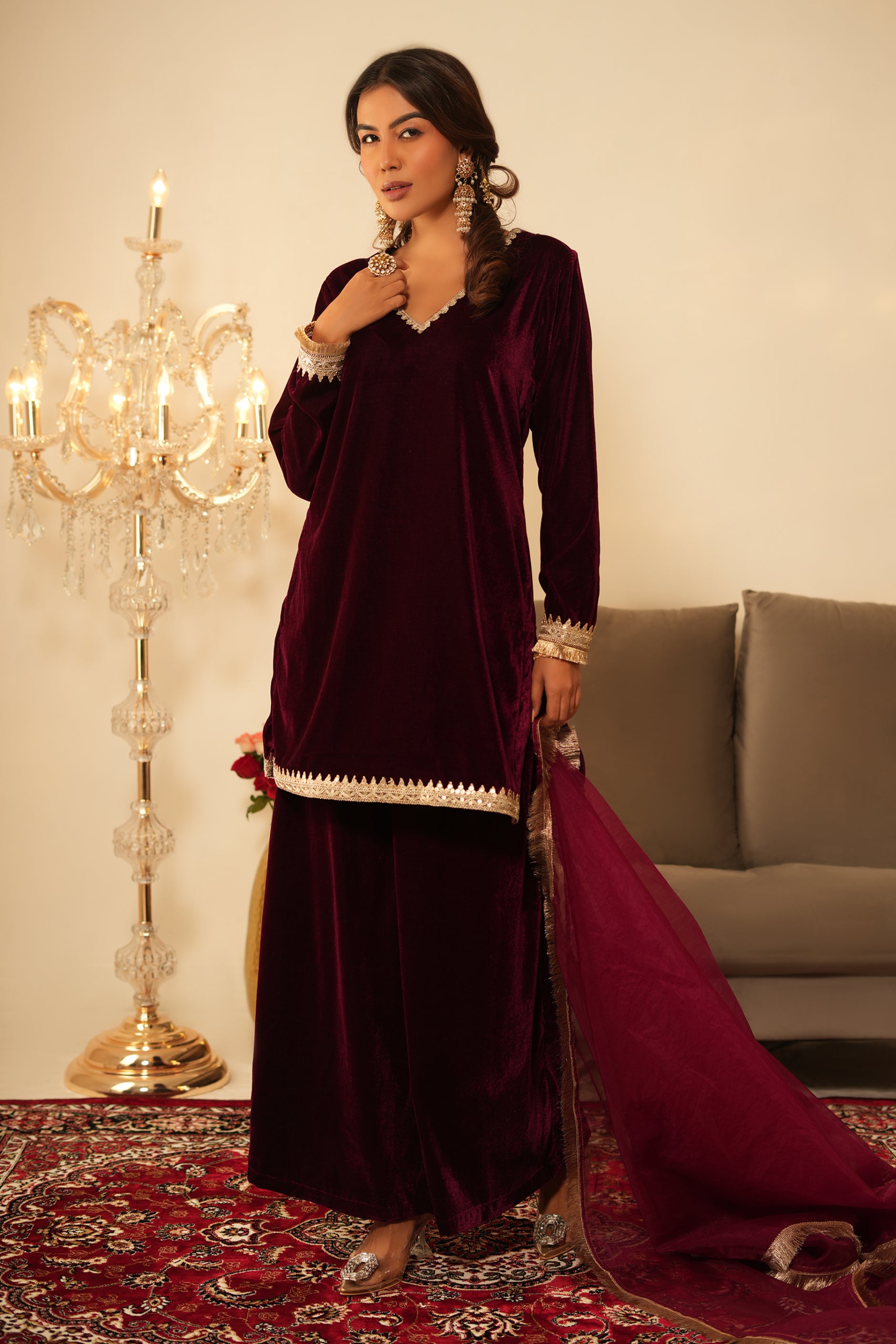 Woman wearing Wine Velvet Kurti with Sharara  featuring gota lace detailing on the sleeves, neckline and hem, V neckline, full sleeves, and matching wine velvet sharara 