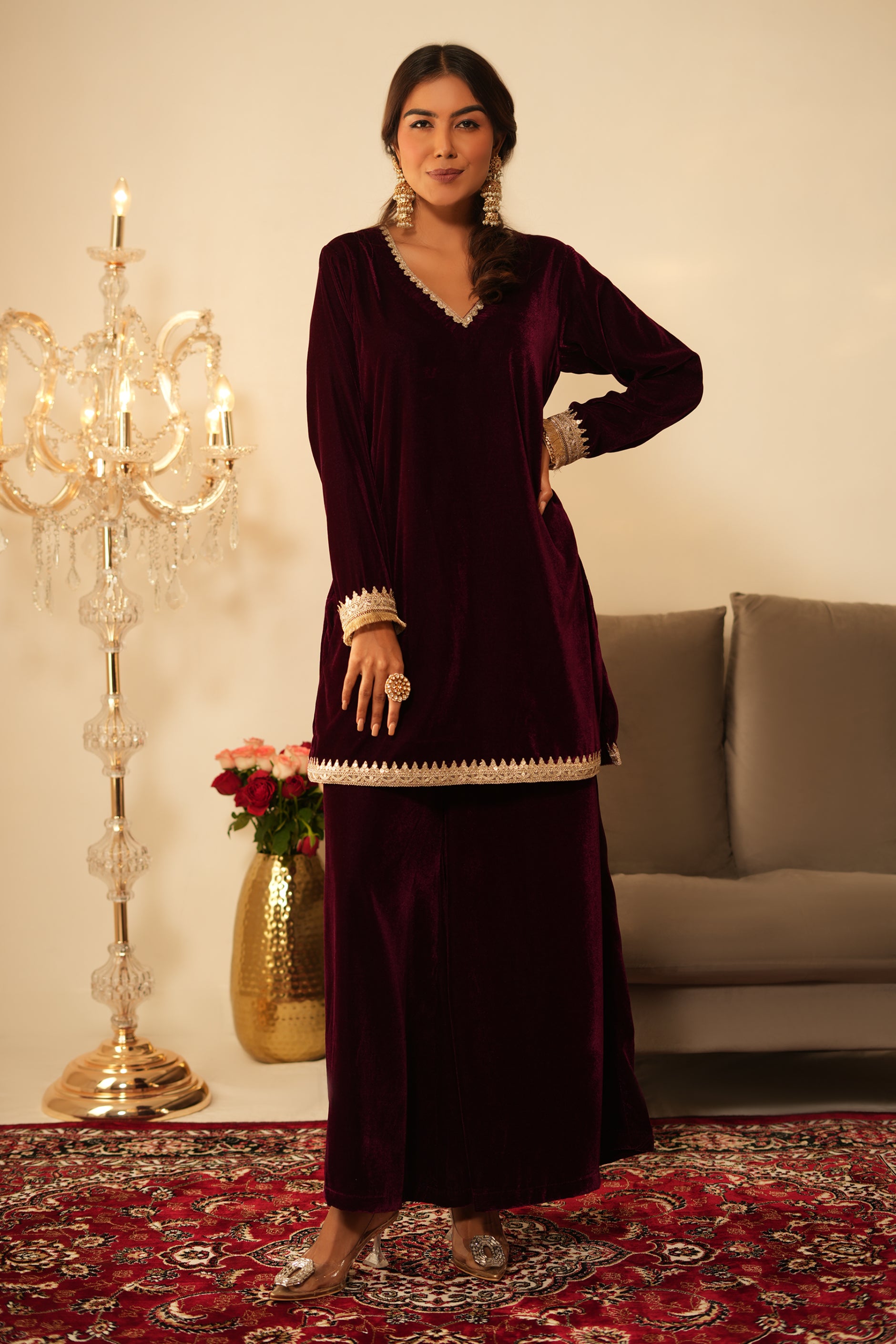 Woman wearing Wine Velvet Kurti with Sharara  featuring gota lace detailing on the sleeves, neckline and hem, V neckline, full sleeves, and matching wine velvet sharara 