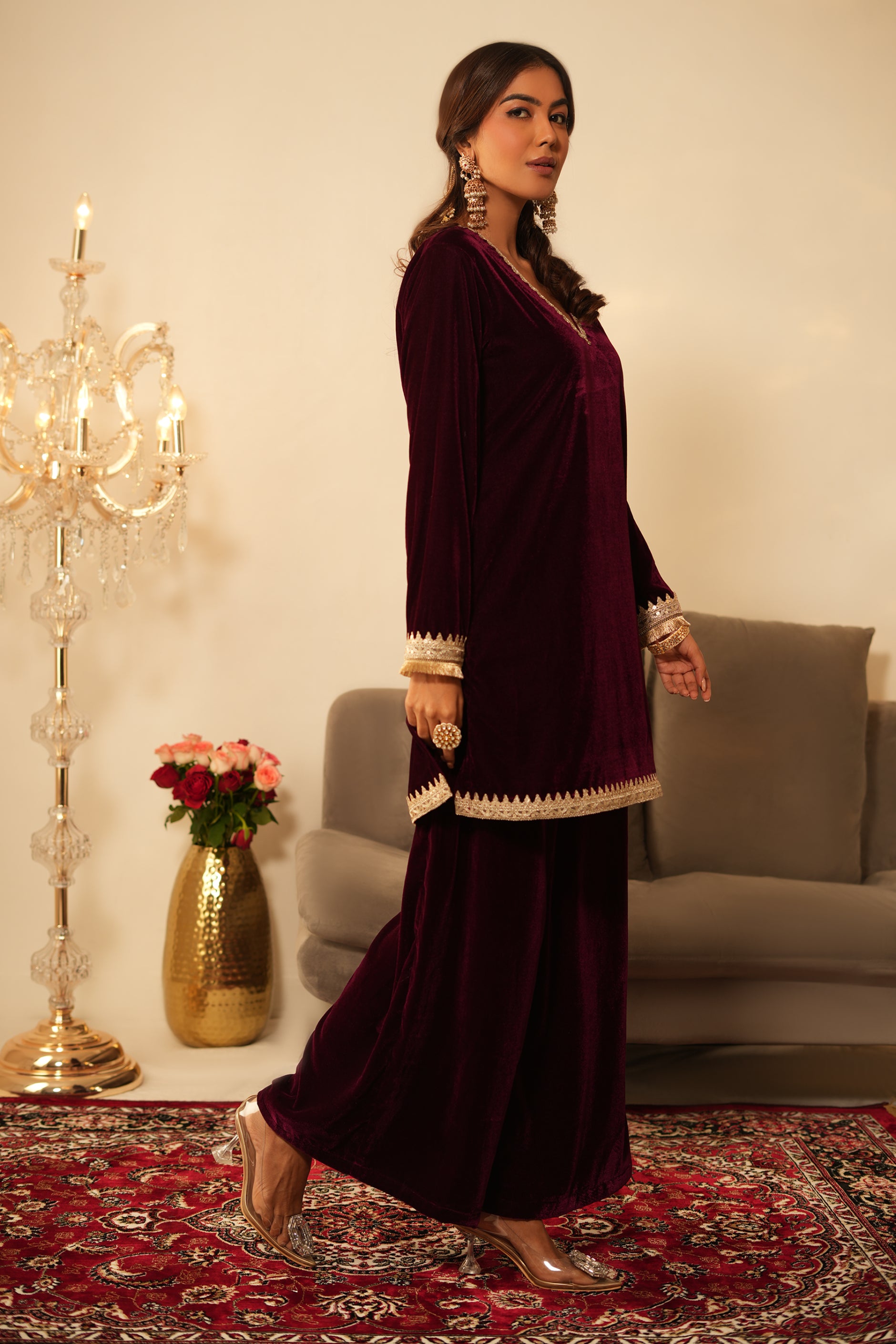 Woman wearing Wine Velvet Kurti with Sharara  featuring gota lace detailing on the sleeves, neckline and hem, V neckline, full sleeves, and matching wine velvet sharara 