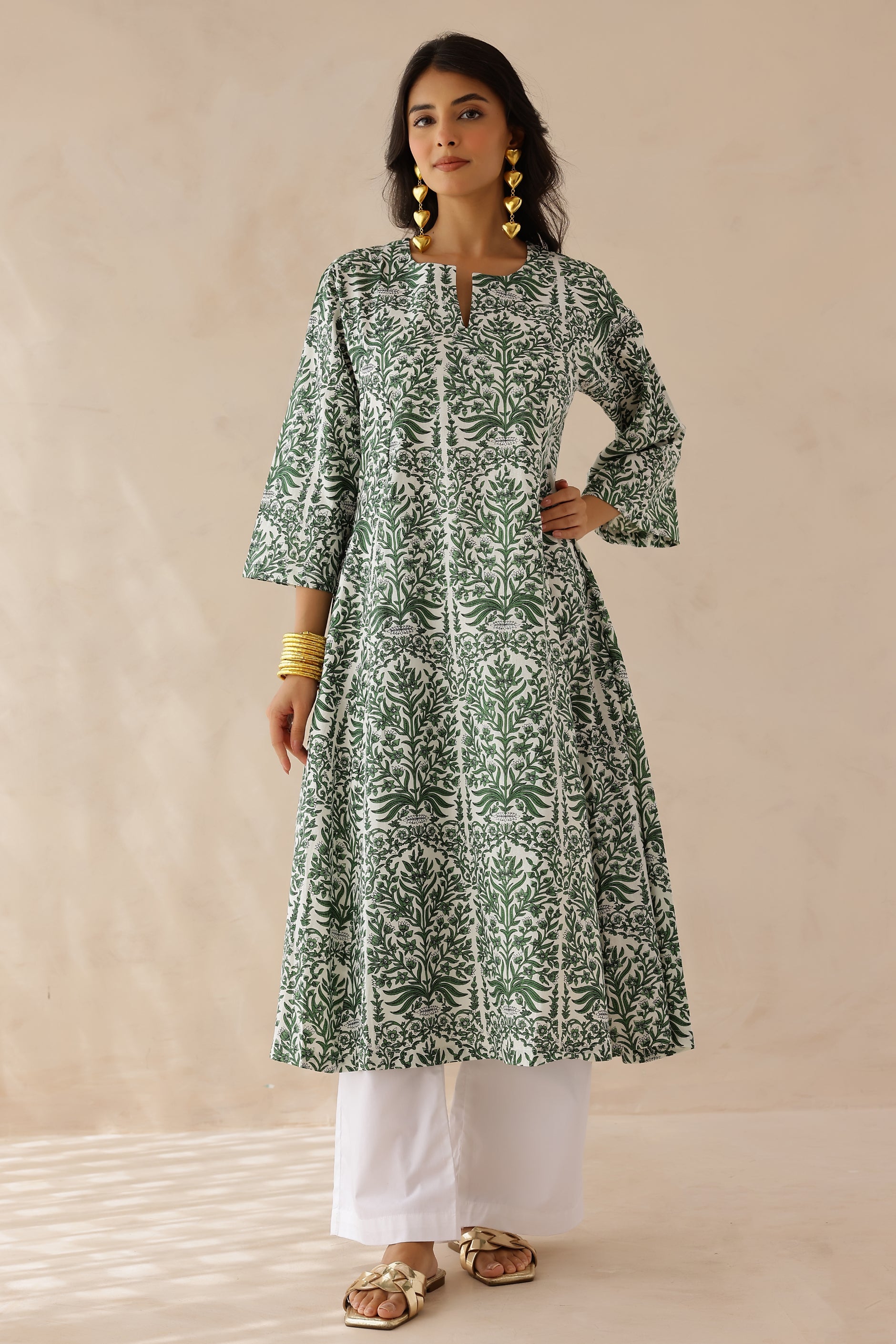 Woman wearing green and white printed cotton kurta with round V-cut neckline, 3/4 sleeves, and white cotton pants.