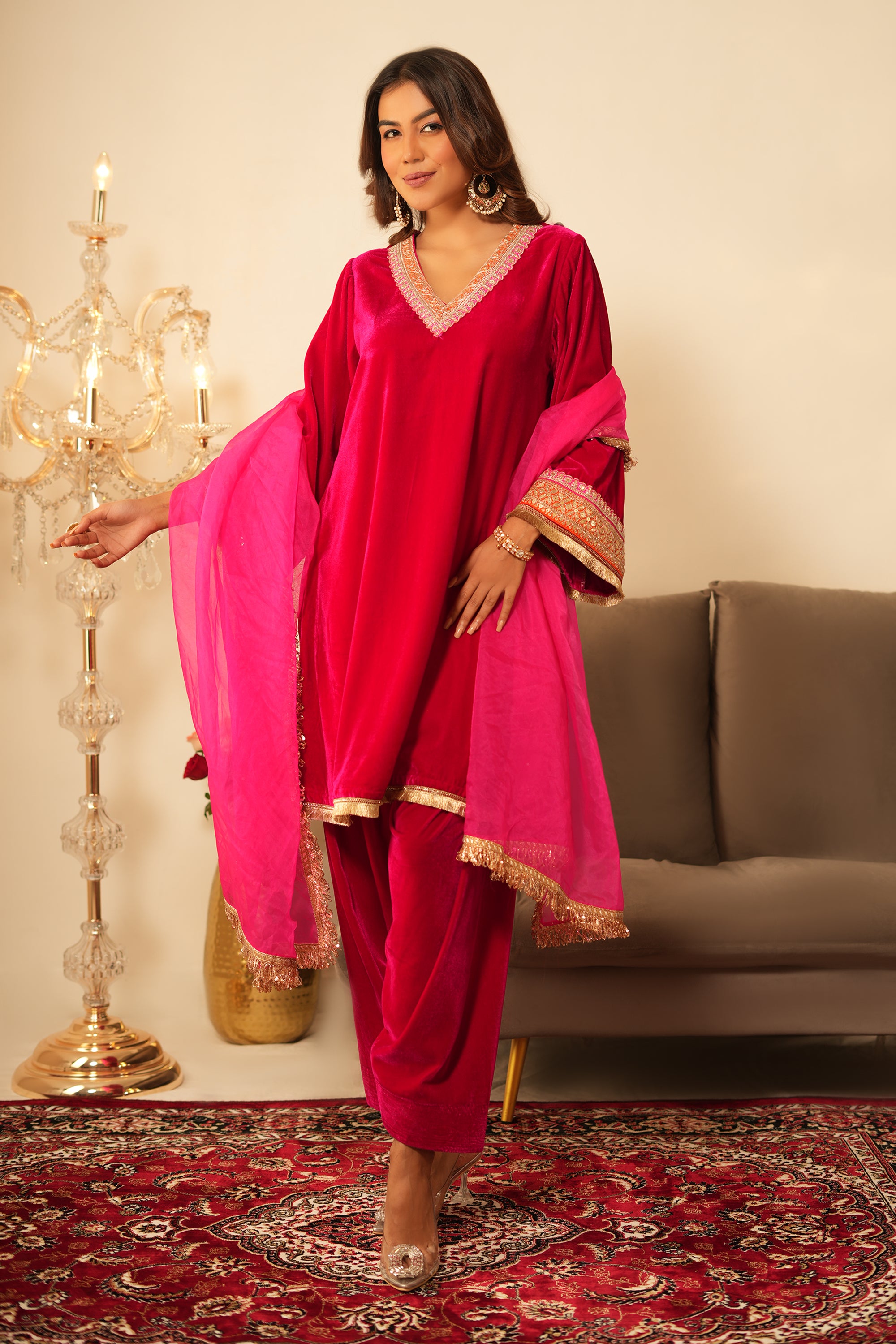 Woman in pink velvet gota lace kurta set with V-neckline, 3/4 sleeves, matching salwar, and organza dupatta.