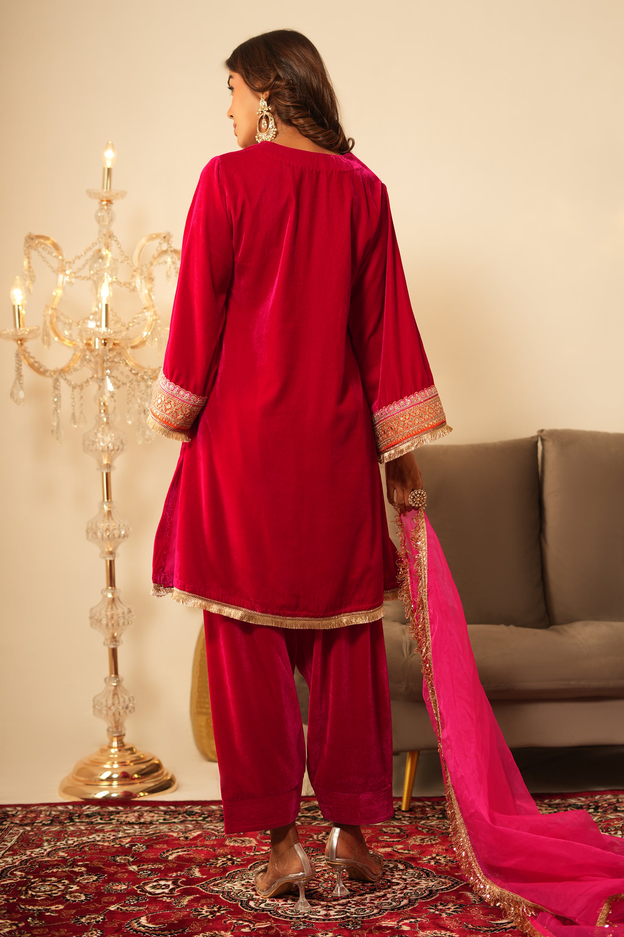 Woman in pink velvet gota lace kurta set with V-neckline, 3/4 sleeves, matching salwar, and organza dupatta.