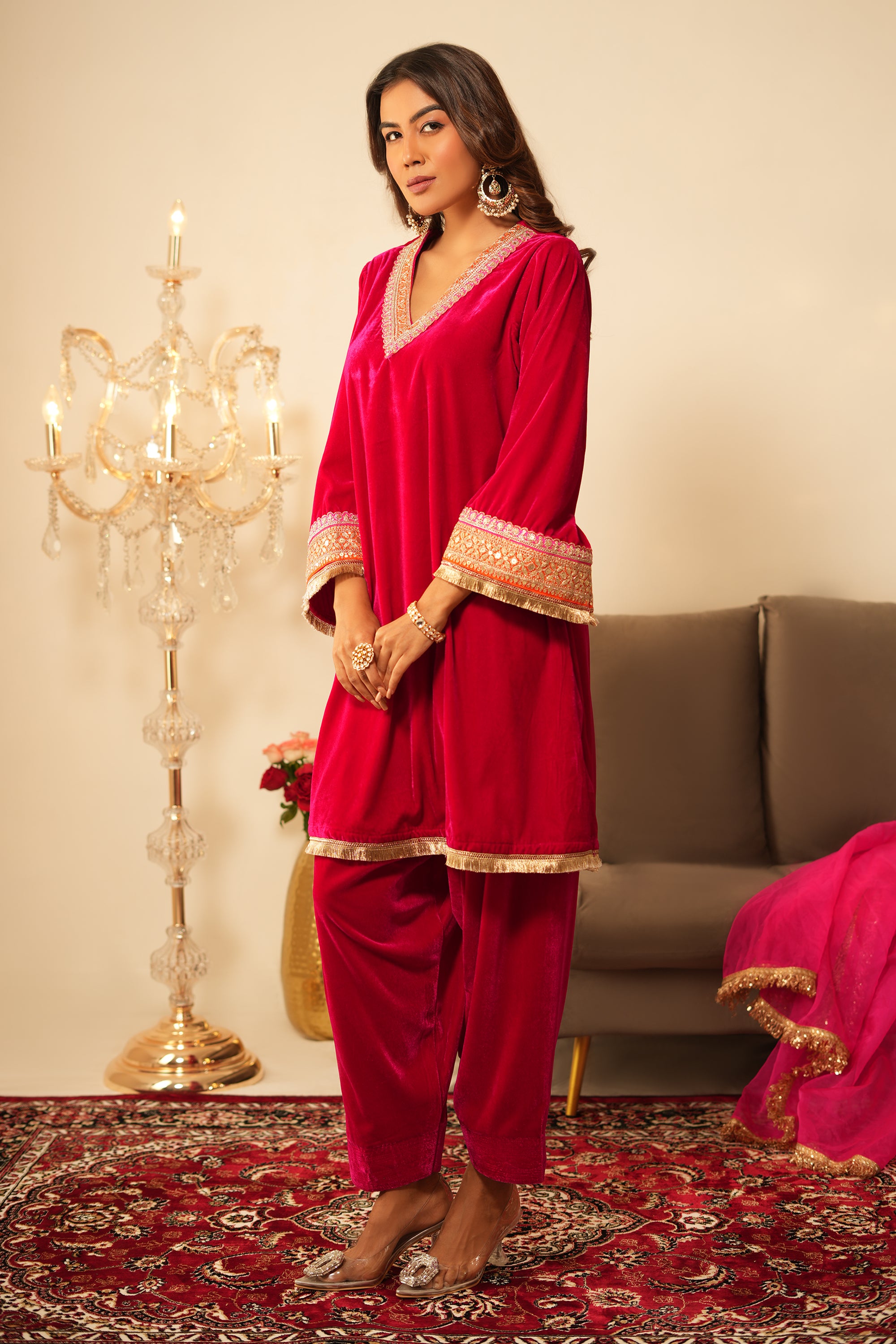 Woman in pink velvet gota lace kurta set with V-neckline, 3/4 sleeves, matching salwar, and organza dupatta.