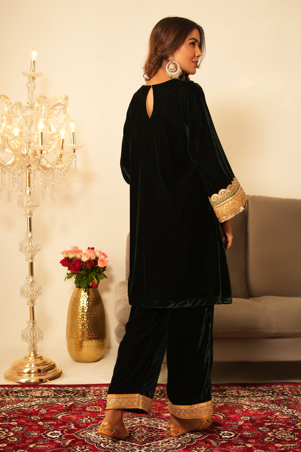 Woman wearing a black dress with gold embroidery in an elegant indoor setting