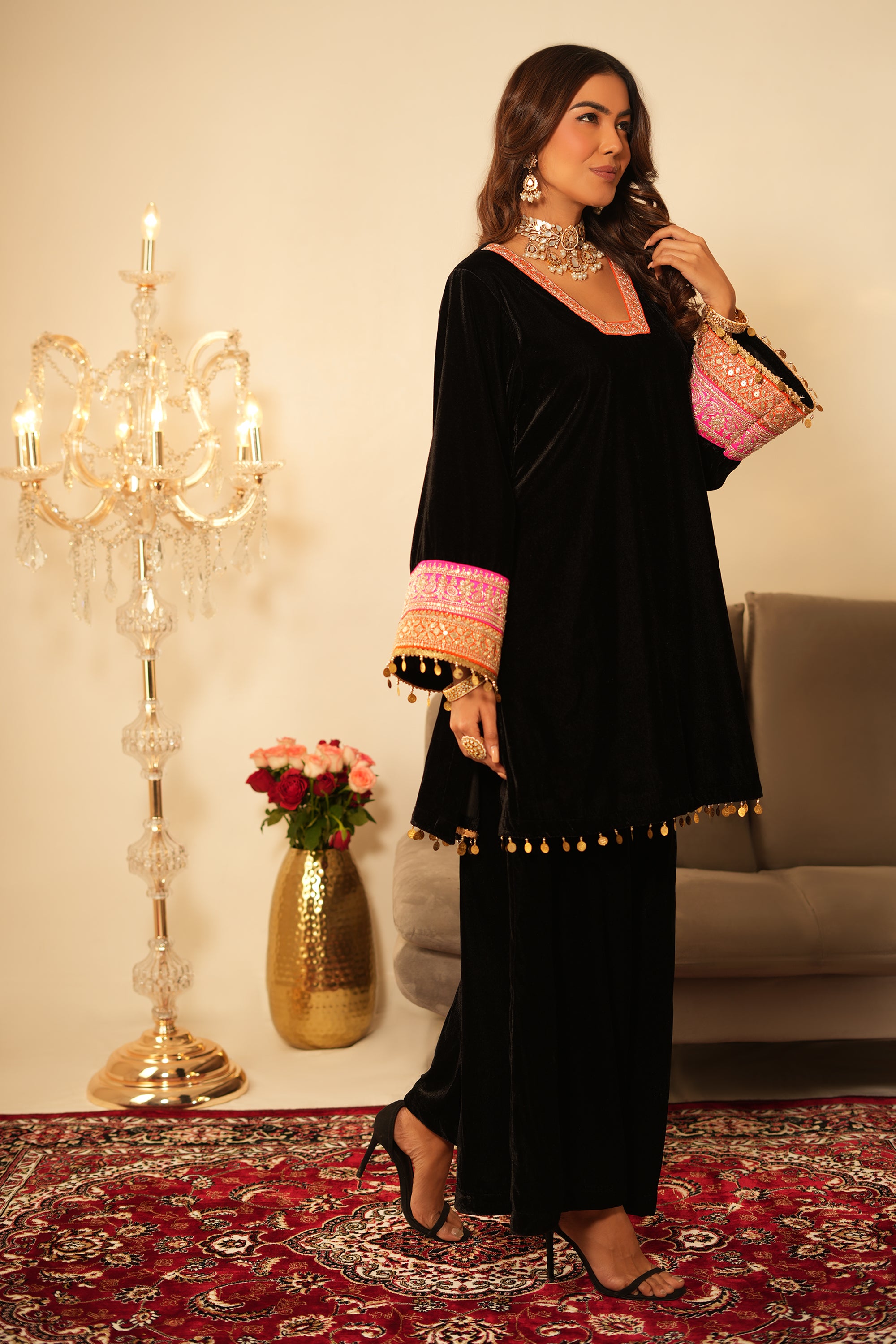 Woman in a black outfit with colorful sleeves standing in a room with decorative elements.