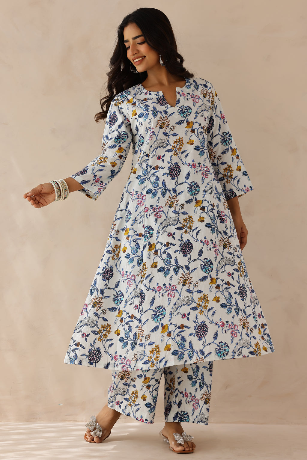 Woman wearing white printed cotton kurta with round V-cut neckline, 3/4 sleeves, and white cotton pants.
