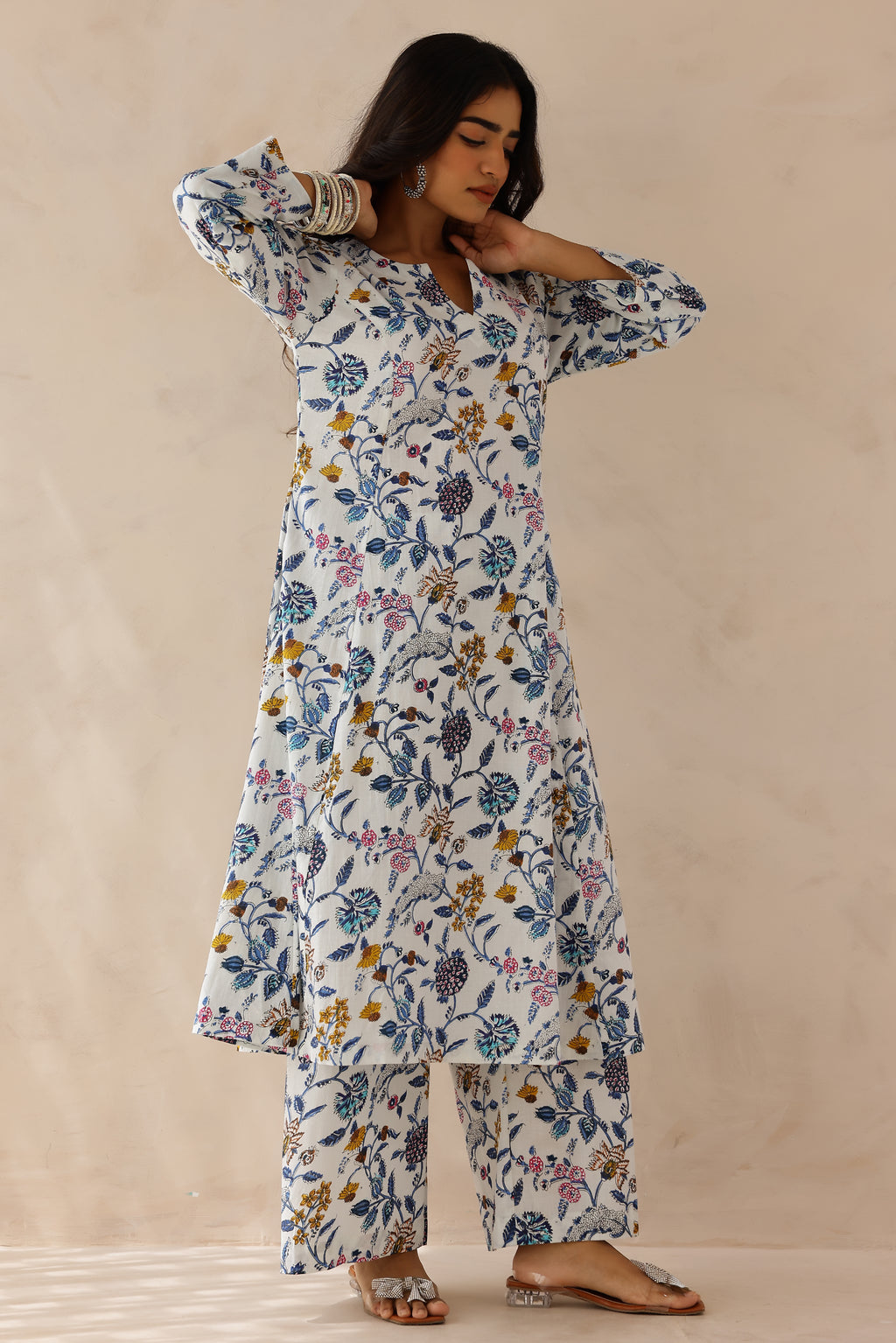 Woman wearing white printed cotton kurta with round V-cut neckline, 3/4 sleeves, and white cotton pants.