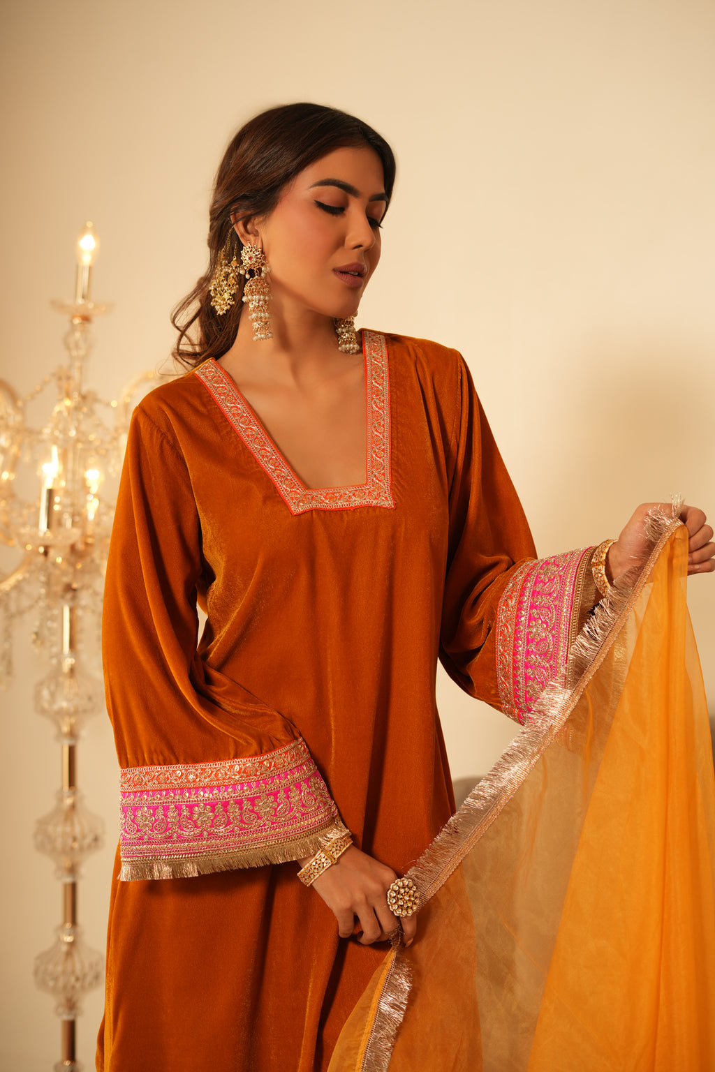 Woman wearing Mustard Velvet Kurta with Pants Set of 2 featuring gota lace detailing on neckline, sleeves and pant hem, blunt V neckline, full sleeves, and matching mustard pants with elastic waist