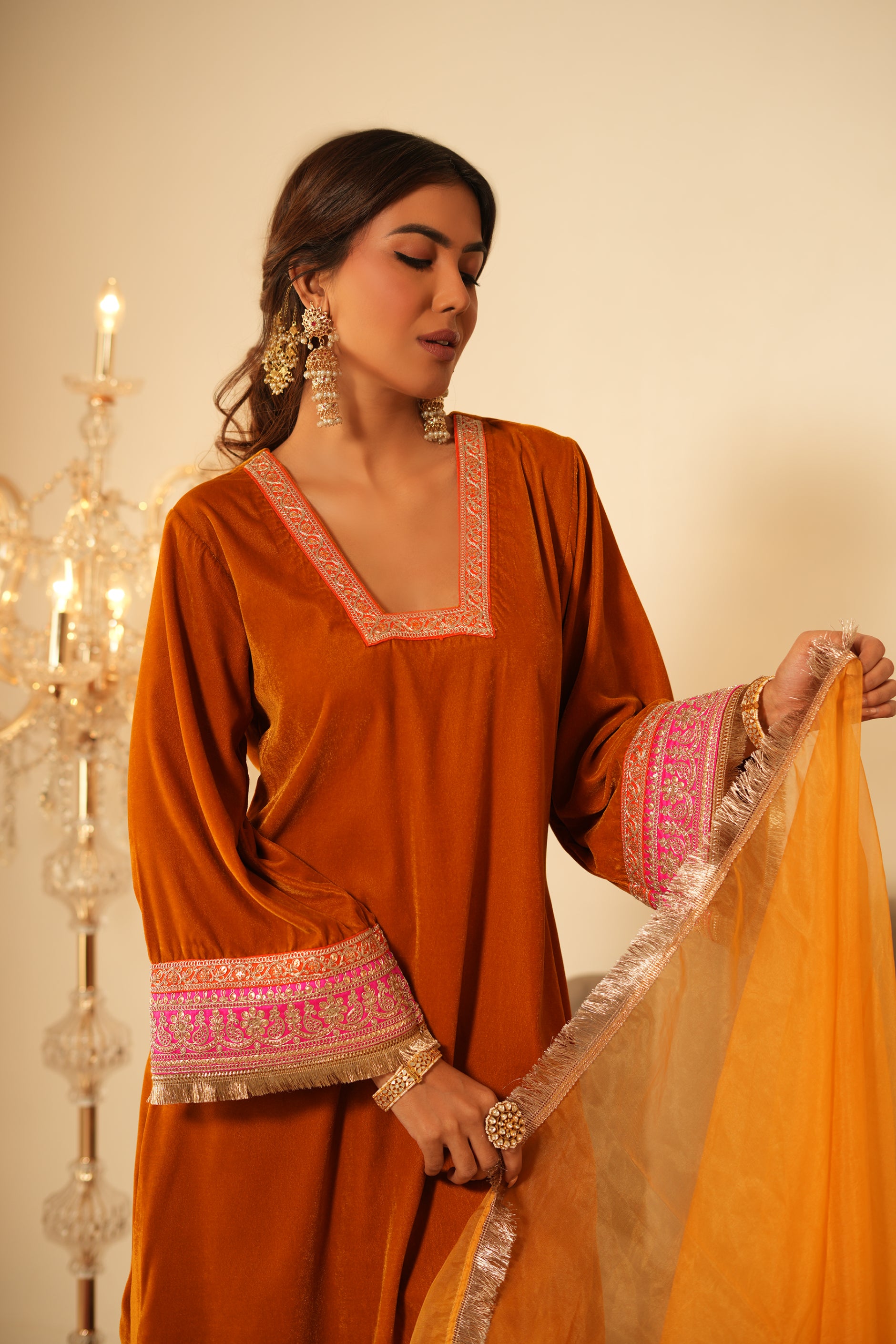 Woman wearing Mustard Velvet Kurta with Pants Set of 2 featuring gota lace detailing on neckline, sleeves and pant hem, blunt V neckline, full sleeves, and matching mustard pants with elastic waist