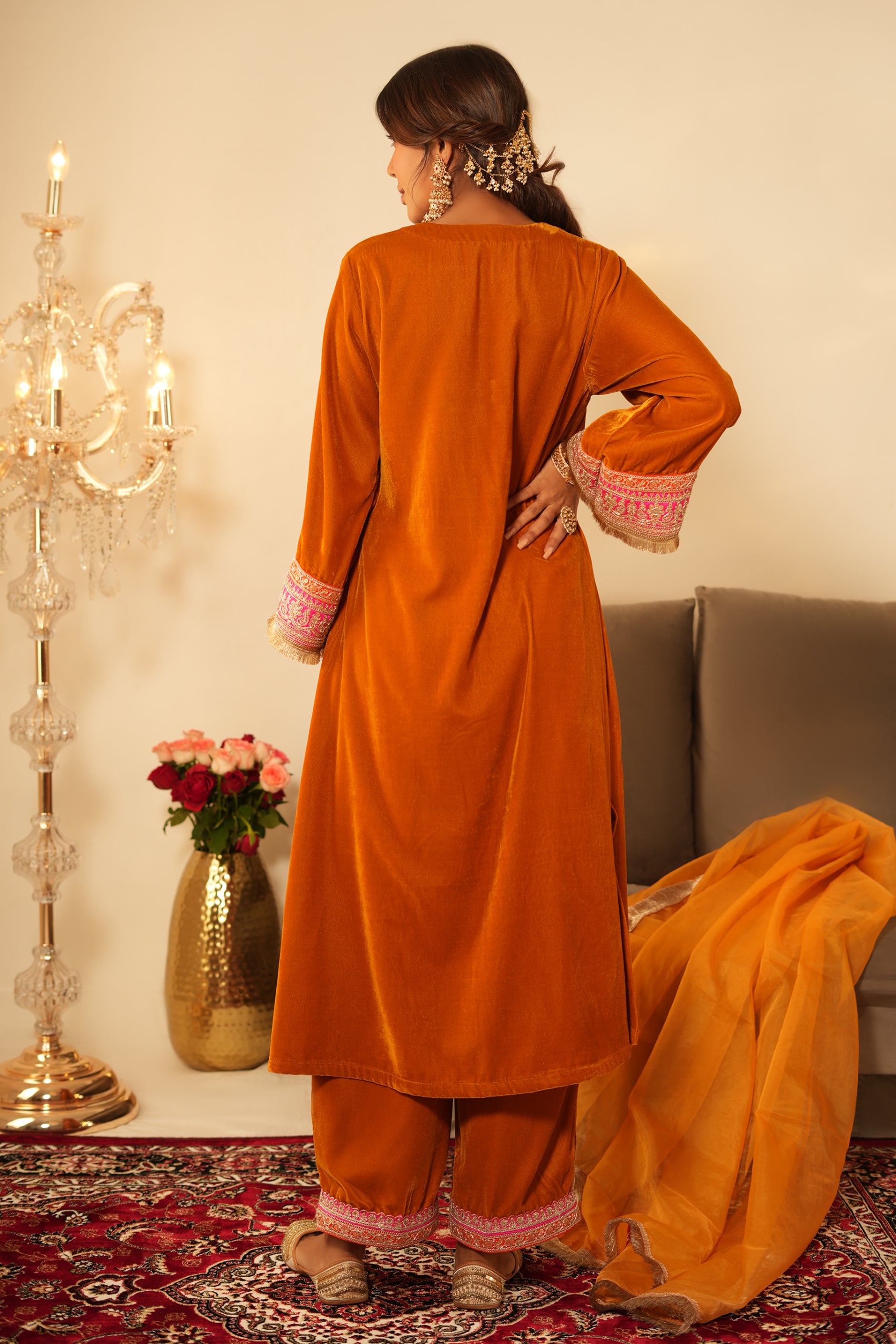 Woman wearing Mustard Velvet Kurta with Pants Set of 2 featuring gota lace detailing on neckline, sleeves and pant hem, blunt V neckline, full sleeves, and matching mustard pants with yellow dupatta